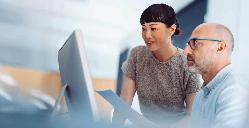 Professionals collaborating at a computer, representing digitally enabled customer experience and human-led transformation.