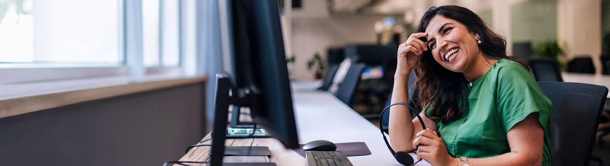 Smiling customer support agent with a headset at her desk