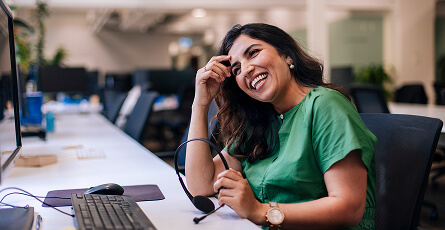 Smiling customer support agent with a headset at her desk