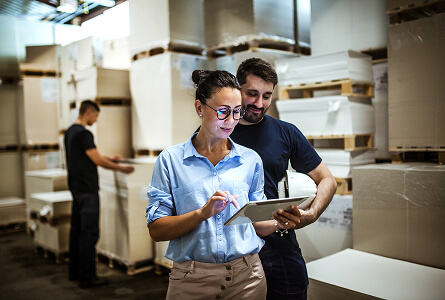 Warehouse supervisor talking with a manager holding a tablet