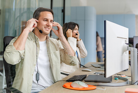 Smiling agent adjusting his headset at his desk