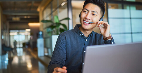 Smiling customer service agent on a headset at a laptop
