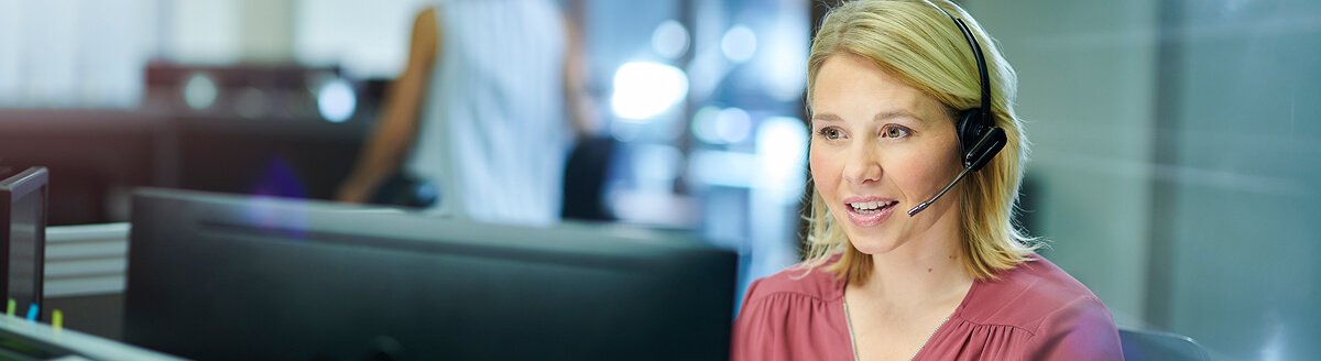 Customer service agent talking on a headset at her computer