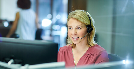 Customer service agent talking on a headset at her computer